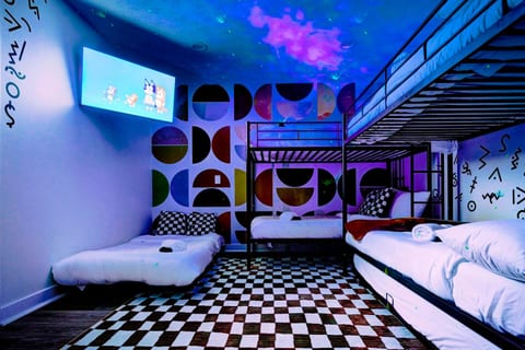 Welcome to the fun and stylish Bunkhouse Room, perfect for groups and comfortably sleeping 6. Featuring mid-century decor, a smart TV, and enchanting nebula lighting for a cozy "movie under the stars" vibe. Includes an attached bathroom as well. 