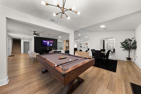 A stylish and modern entertainment space featuring a sleek pool table, elegant lighting, and an inviting open-concept design.