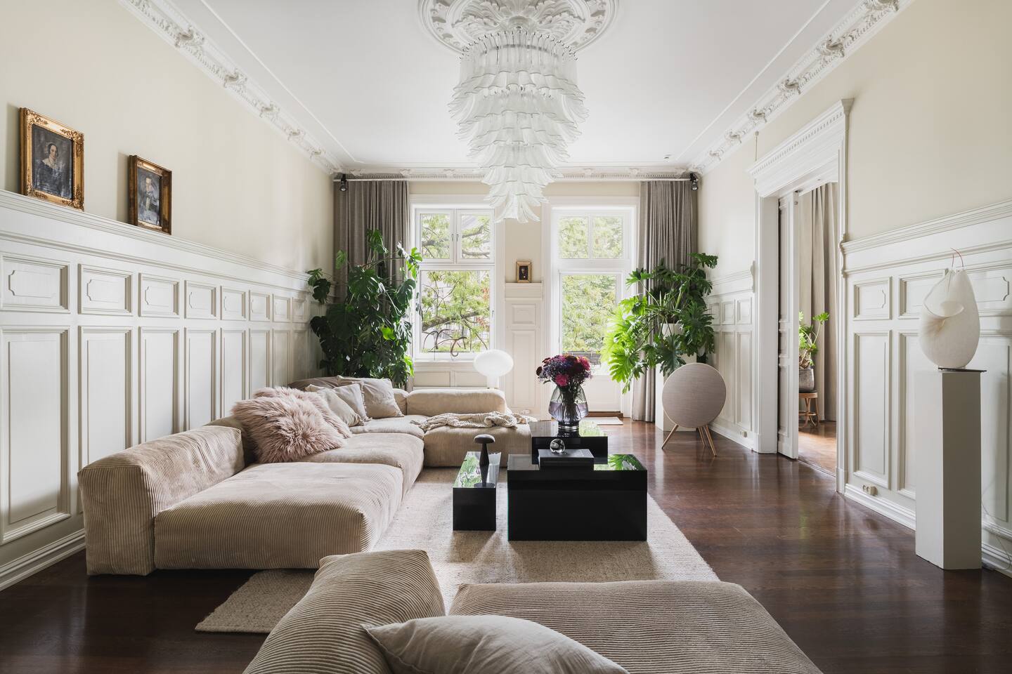 Tenk deg at du synker ned i de myke sofaene i denne elegante stuen, badet i naturlig lys fra de store vinduene. Med frodig grønt, sofistikert innredning og utgang til balkong er det perfekt for avslapning og samtale.