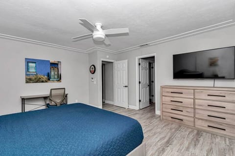 Master bedroom complete with King sized bed and pillows, two large windows, black out shades, smart TV, work desk, ceiling fan with lights, two floor fans, and walk into your private bathroom, with a large walk in closet.