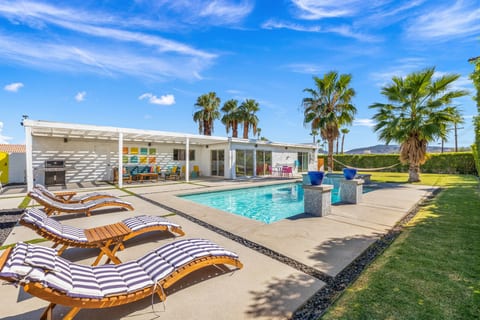 Sun-soaked backyard w/ sparkling pool, loungers, & desert landscaping made for laid-back Palm Springs days.