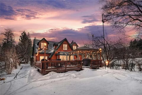 Storybook cabin exterior glowing at dusk, framed by trees and fresh snow.