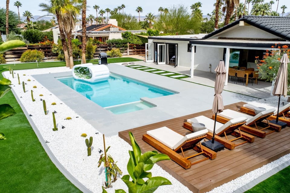 Sun-soaked pool w/ loungers, umbrellas & palm-lined greenery for laid-back days in the desert breeze.
