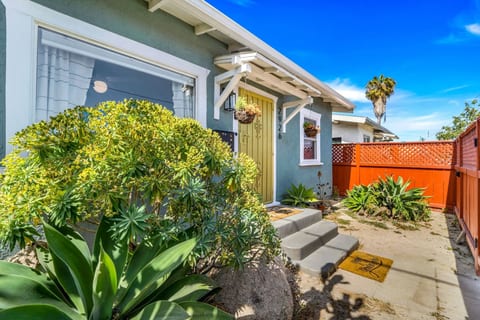 Charming exterior view w/ lush greenery, warm tones & inviting curb appeal.