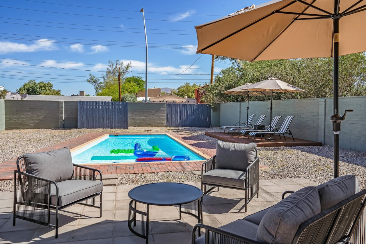 Sun-soaked backyard w/ sparkling pool, comfy lounge seating & shaded dining for relaxed desert afternoons.