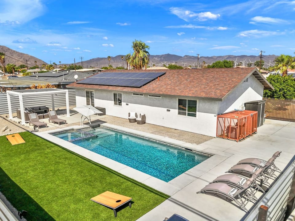 Bird’s-eye view of the desert retreat w/ private pool, sun loungers, and relaxed outdoor spaces framed by mountain skies.
