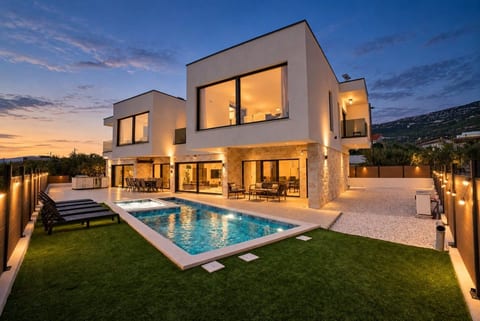 Twilight over a luxury villa with glowing pool and lush private garden