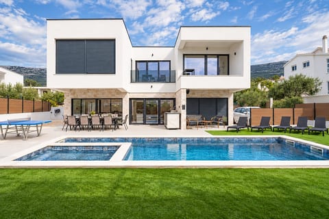 Modern villa with heated pool, whirlpool and sun loungers under blue skies