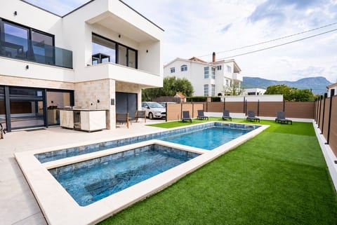 Private pool and whirlpool framed by an outdoor kitchen and lush lawn