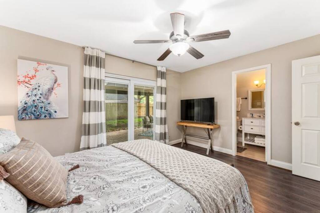 Private Suite with Queen bed & Night- Stand Lamps, Working Area, 50"TV and attached Full clean bathroom looking over to the backyard of house