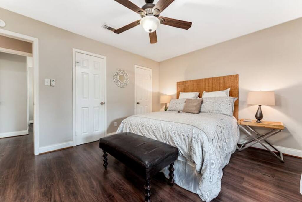 This cozy bedroom offer a ceiling fan for comfort, and soft, complete bedding with side lamps