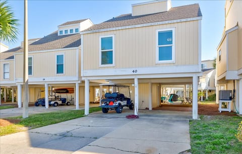 A front view of the property, showcasing its charming coastal design with elevated parking underneath. The designated parking area includes space for vehicles, golf carts, and boat trailers (up to 30 feet long).