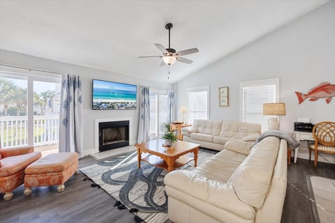 A closer view of the living room's cozy seating area, emphasizing the plush furniture and tasteful decor. The large flat-screen TV and fireplace make this space ideal for relaxing after a day at the beach.