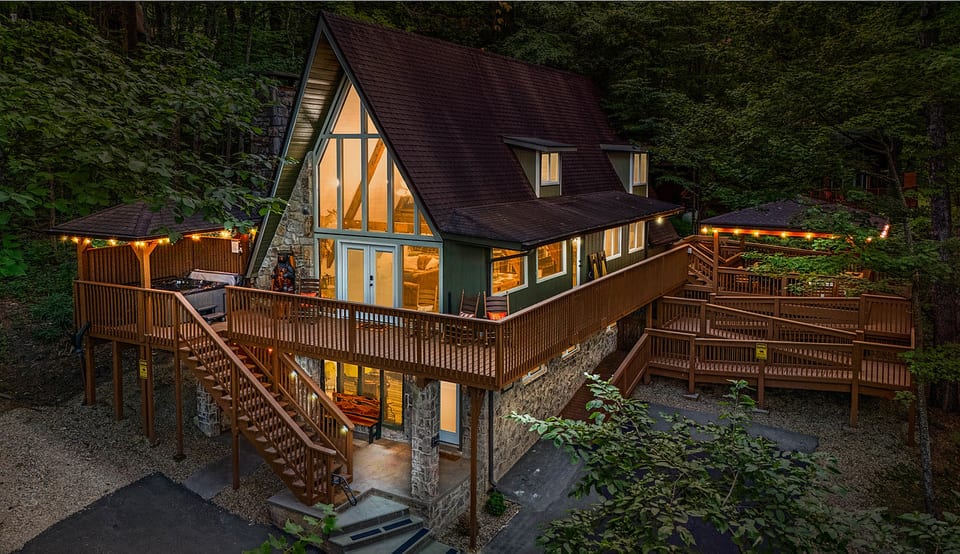 A-frame lit up at dusk, with a wrap around deck and handicap ramp