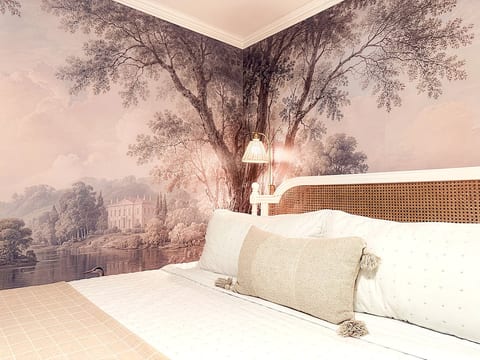 A custom wallpaper mural creates a magical, storybook experience in the primary bedroom. Every detail thought of, this room will be your refuge. Pottery Barn bath robes, smart TV, en suite bathroom, linens, towels, toiletries, and more.