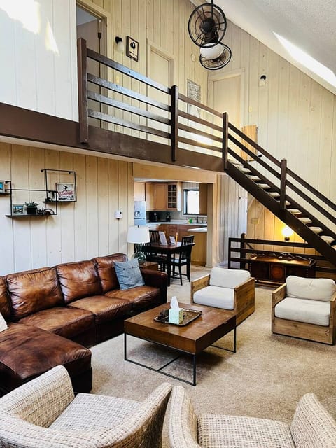 Main living area with large couch and 4 lounge chairs, fireplace and TV