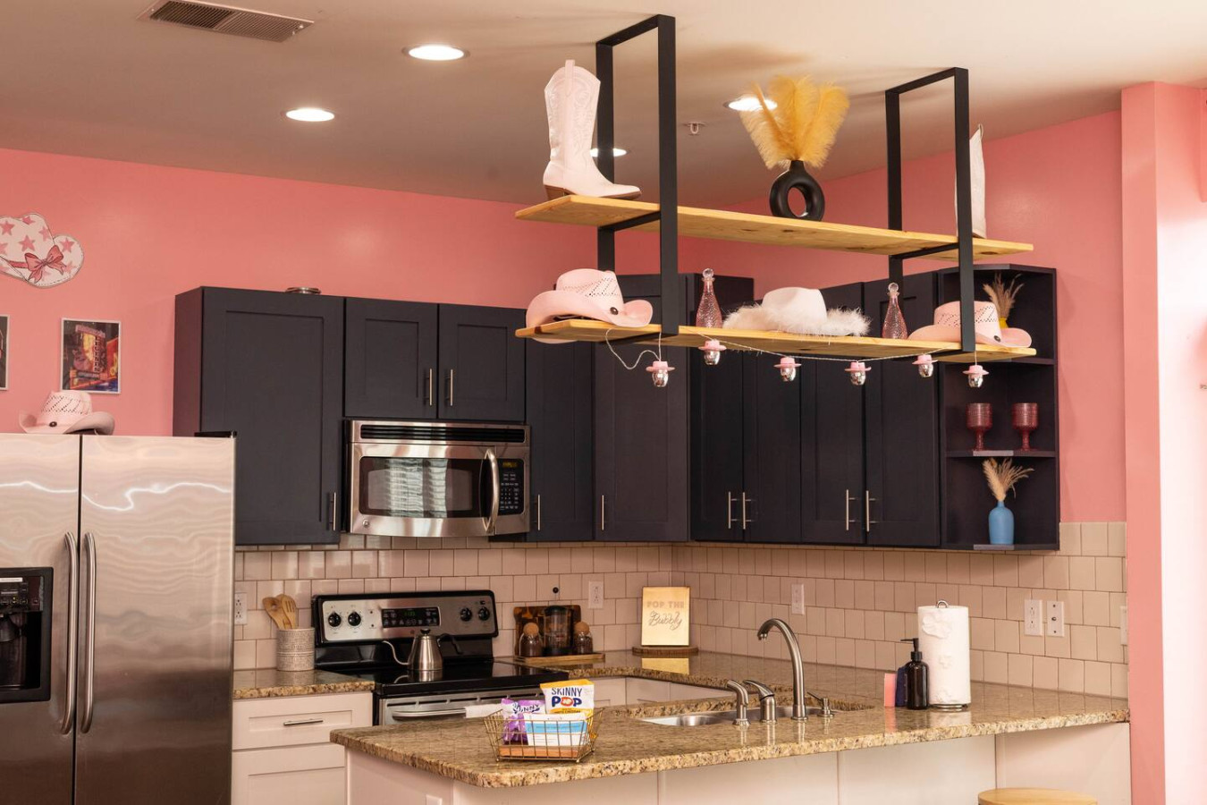 Sassy meets stylish in this fully equipped kitchen with dark cabinetry, granite counters, and whimsical pink-and-white cowgirl hat accents. Whether you’re cooking or just pouring champagne, it’s all part of the fun.