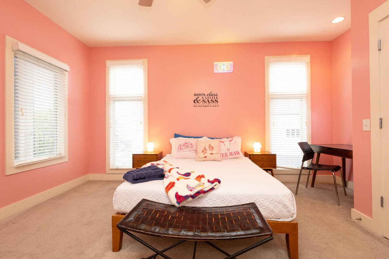 With its neon “HOWDY” sign, playful pillows, and pink walls, this bedroom screams Nashville bachelorette. A plush queen bed ensures comfort while the décor brings the sass.