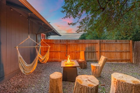 Propane firepit in the fenced backyard w/ ambiance lighting and hammock swings