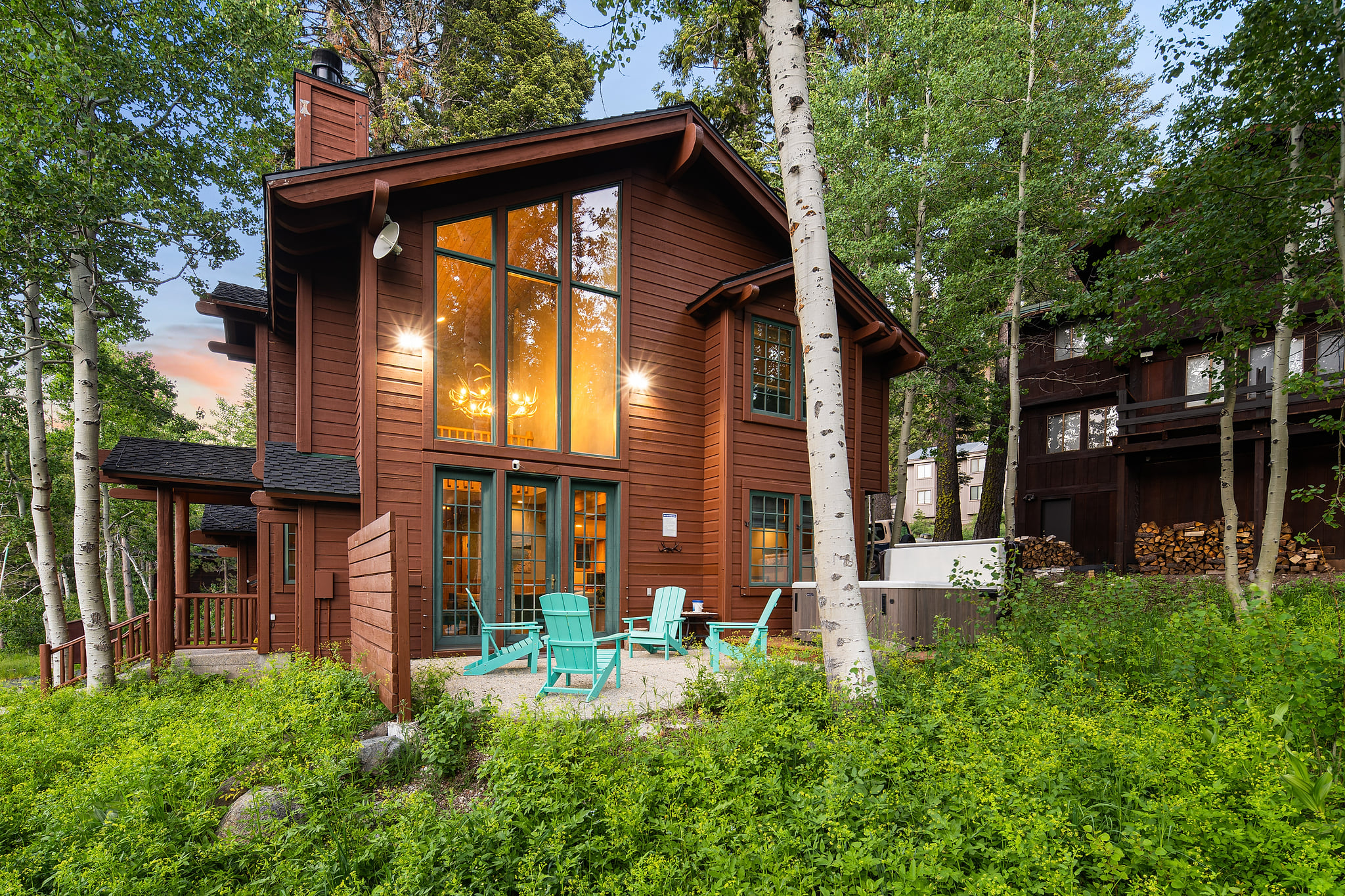 Where the indoors meets the outdoors. ✨🌲
As the sun sets, watch the cabin glow from the comfort of the back patio. With the bright turquoise Adirondack chairs and the hot tub ready to go, this is the ultimate spot to swap stories under the evening sky.