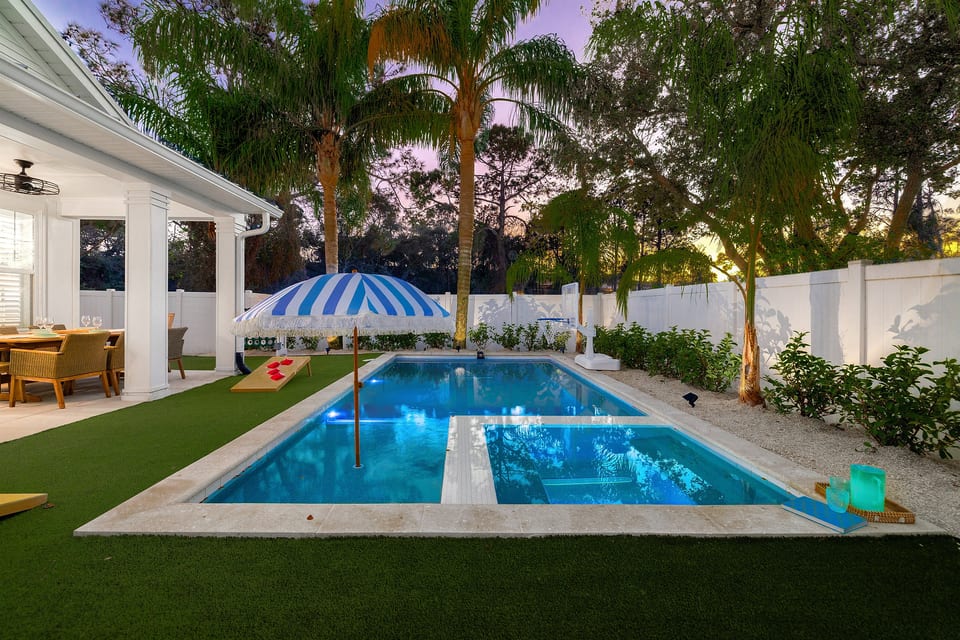 Private backyard oasis with sparkling pool, lush landscaping, and serene evening ambiance