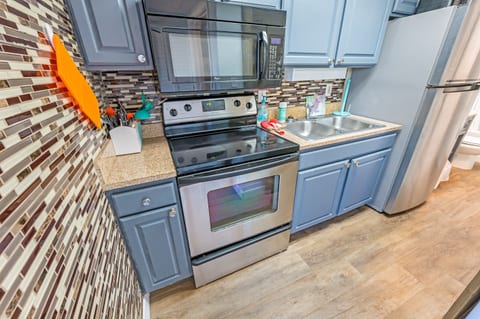 - Fully equipped kitchen with modern appliances, perfect for preparing home cooked meals - Stylish backsplash and blue cabinets bring a fresh and inviting touch - Whether cooking a full meal or just reheating, this space makes it effortless