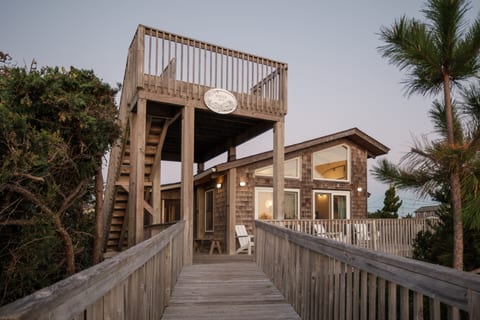 Elevated exterior walkway leading to the home, surrounded by natural greenery.