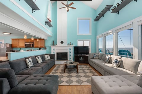 Bright living room w/ comfy seating, coastal accents, & large windows that bring in natural light.