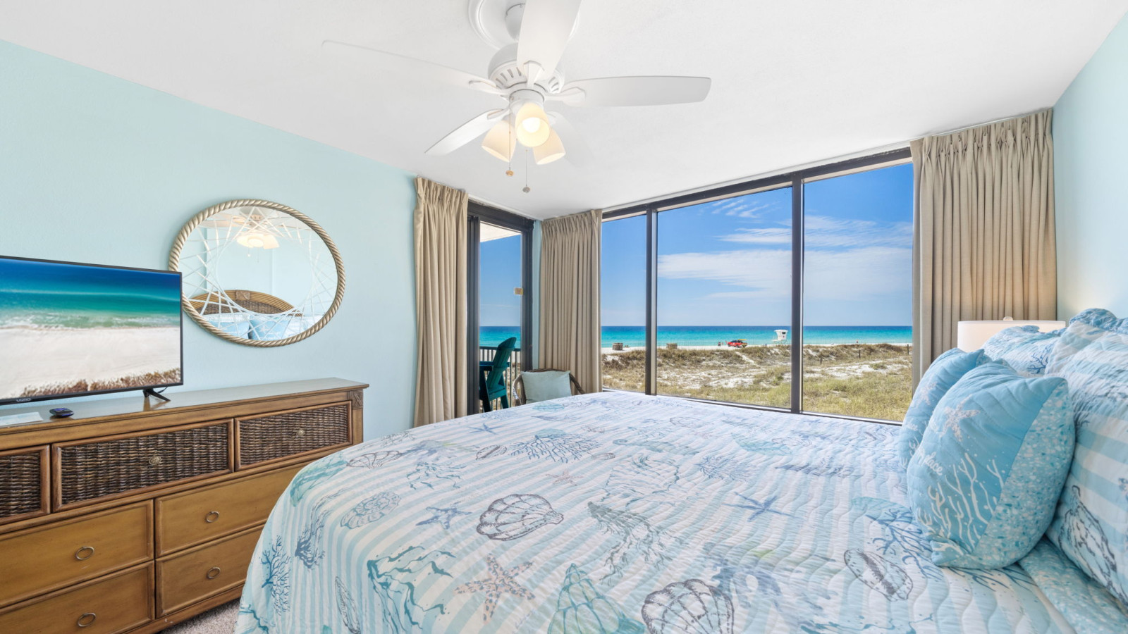 Wake up to breathtaking beach views in this bright, coastal-themed bedroom with floor-to-ceiling windows.