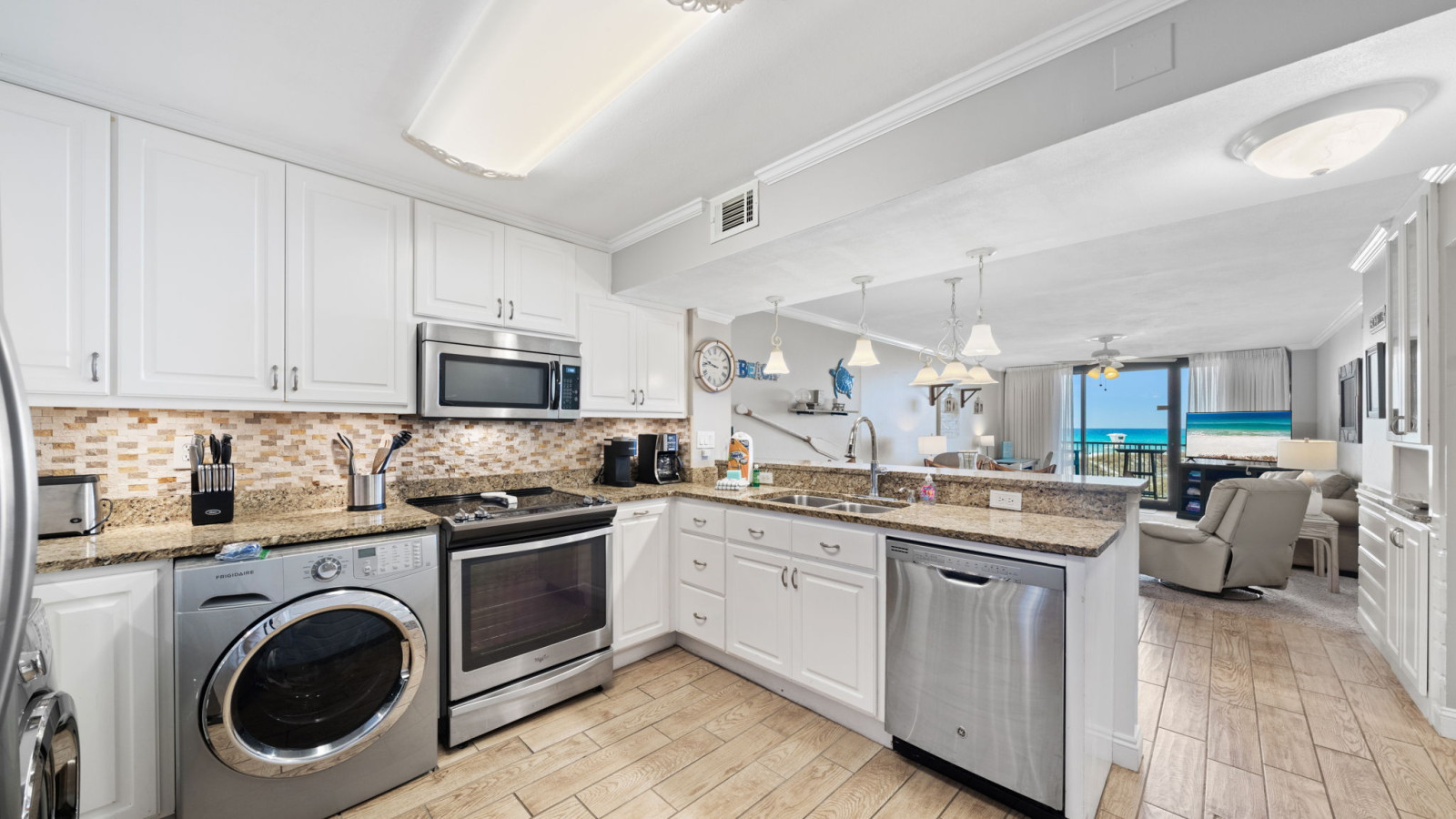 This open kitchen features stainless steel appliances, granite countertops, in-unit laundry, and ocean views.