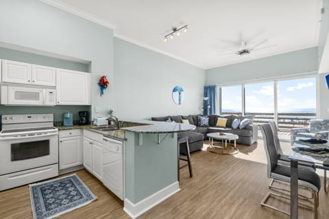 Enjoy the open-concept living space with a fully equipped kitchen, comfortable seating, and stunning ocean views through floor-to-ceiling windows