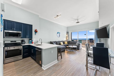 Open-concept living space with modern kitchen, dining area, and direct access to the beachfront balcony.