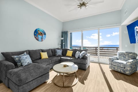 Relax in this inviting living area with floor-to-ceiling windows, offering stunning ocean views and direct access to the beach