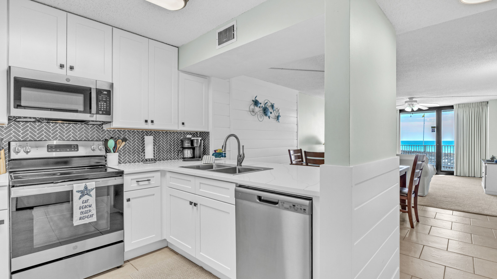 This modern kitchen features white cabinetry, stainless steel appliances, and a stylish chevron tile backsplash for all your cooking needs.