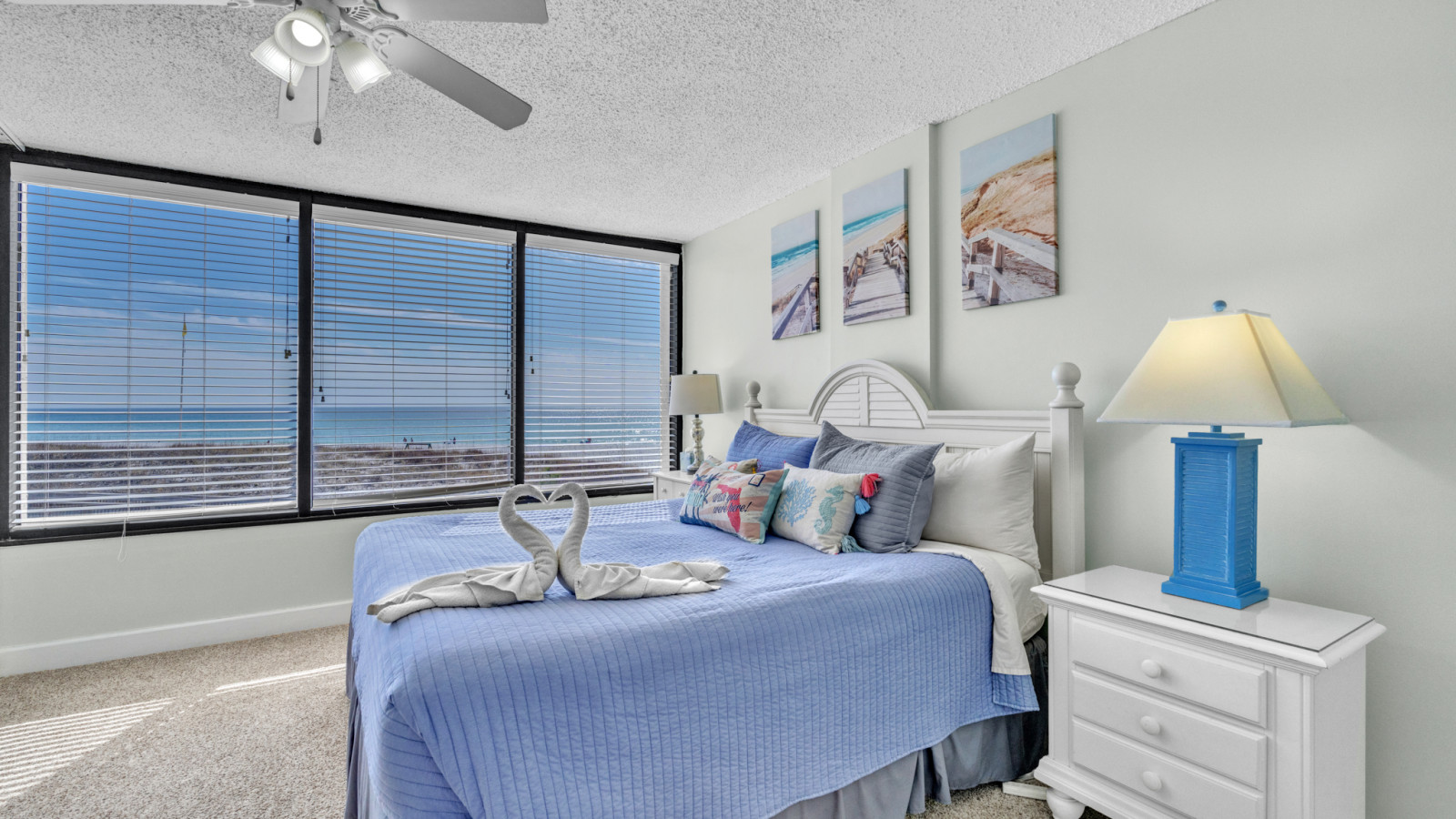 Wake up to breathtaking beach views in a bright primary bedroom with large windows and a king bed dressed in ocean tones.