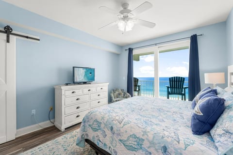 spacious master bedroom features a king-sized bed, coastal decor, and direct balcony access with serene ocean views