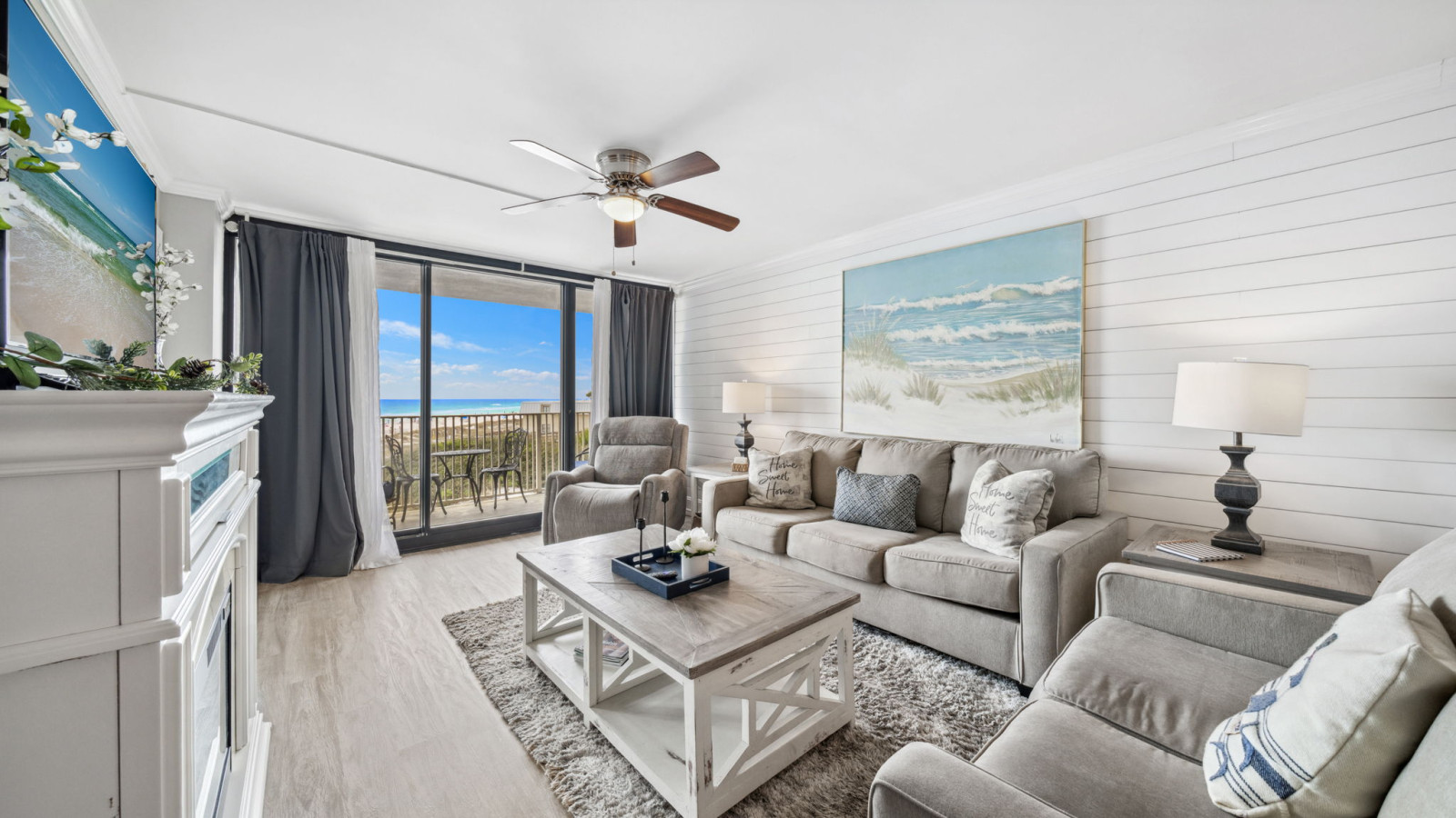This stylish living room offers plush seating, coastal décor, and a sliding door opening to beachfront views and ocean breezes.