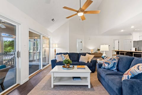 Colorful and light-filled living room with vaulted ceiling and sliding glass doors that lead to the screened in porch.