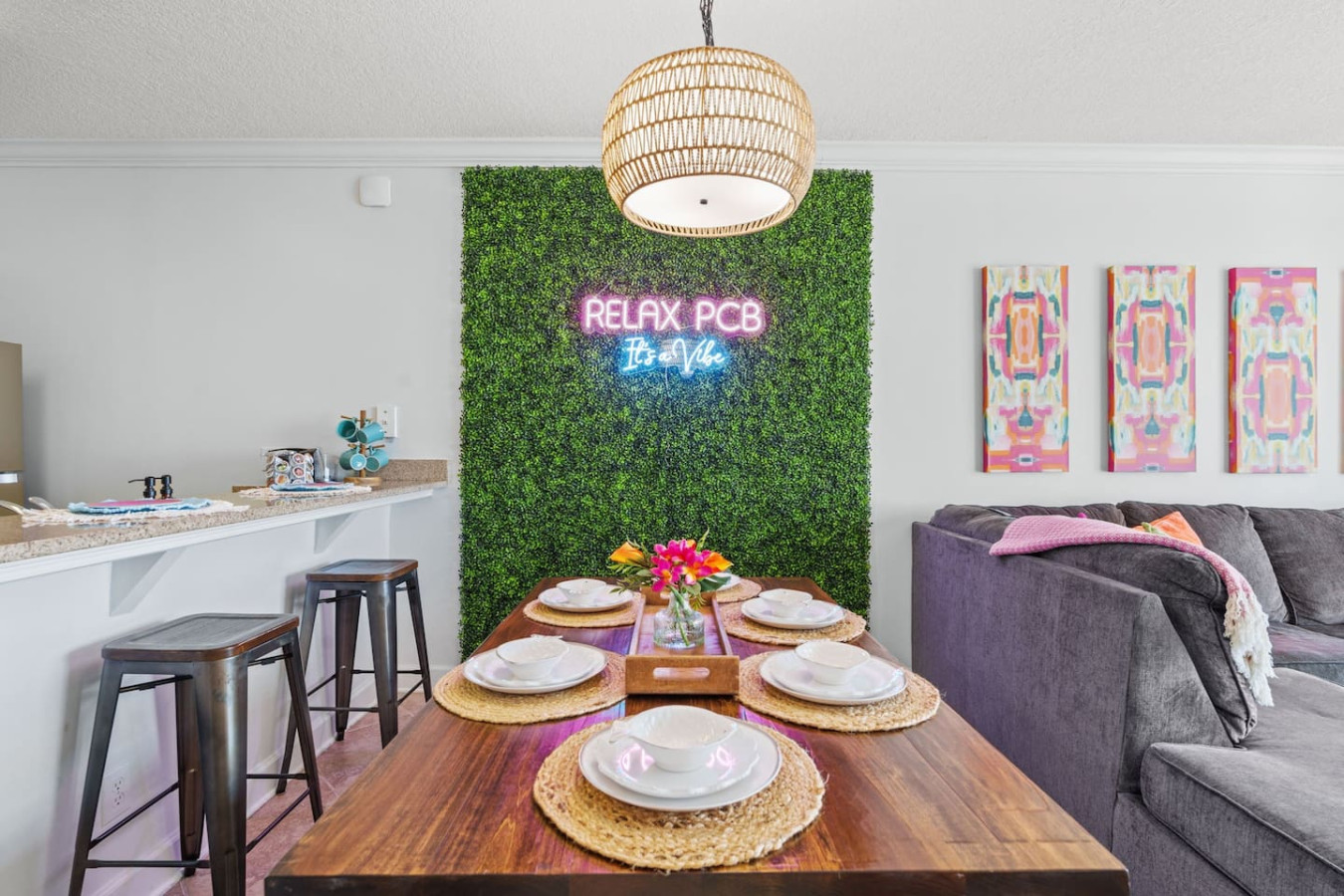 Dine in style in this vibrant and inviting space, featuring a chic wooden table, cozy seating, and a trendy "Relax PCB, It's a Vibe" neon sign that sets the perfect mood for your getaway