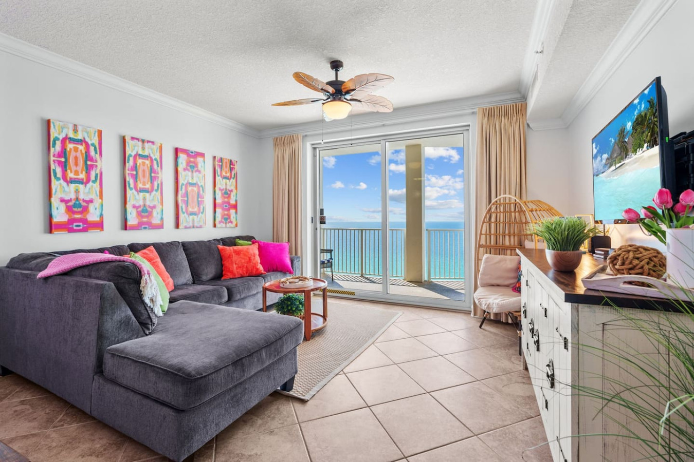 Relax in this stylish and spacious living room, featuring a plush sectional, vibrant décor, and breathtaking floor-to-ceiling ocean views from your private balcony.
