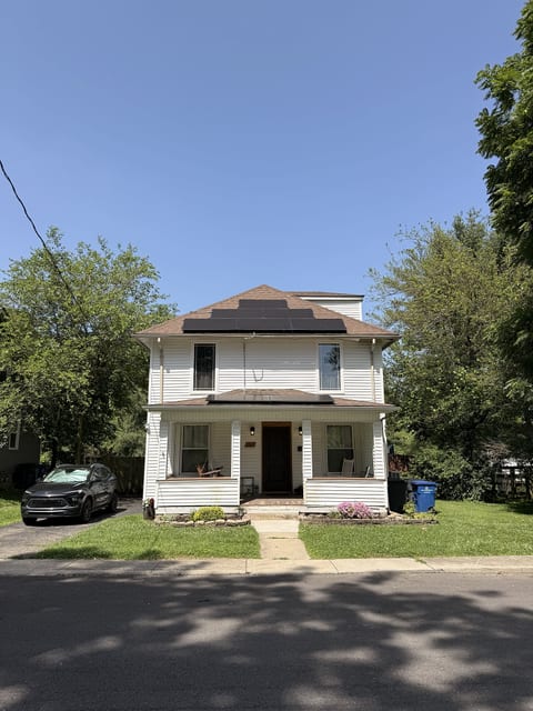Charming two-story home with porch, driveway, and leafy curb appeal
