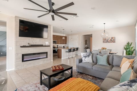 Modern living room with queen sofa bed, 65” TV + sound bar, electric fireplace, and arcade machine. A cozy spot for family fun or relaxing nights.