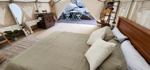 A spacious wall tent with a mirror, coffee station and shelving storage