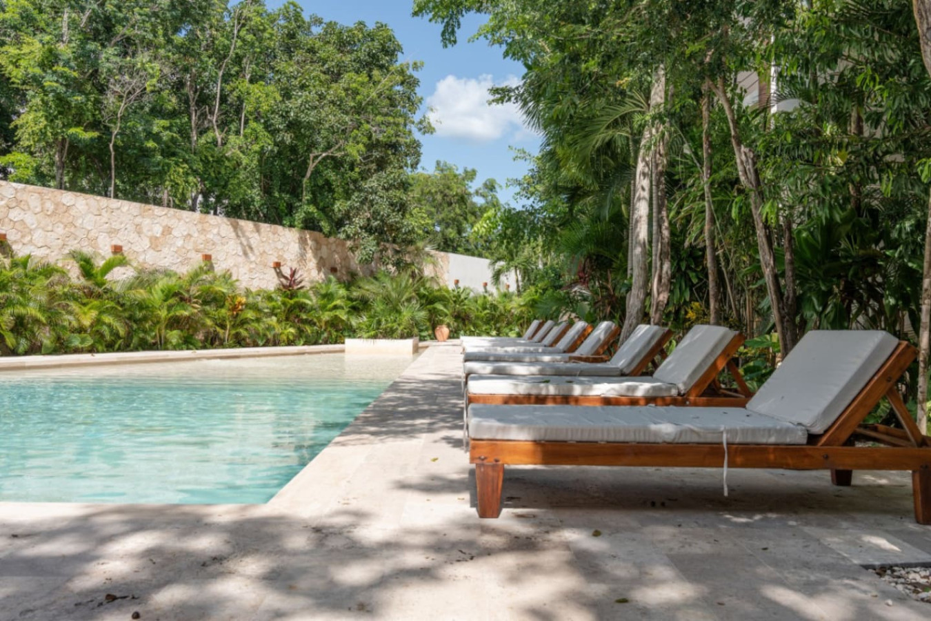 Enjoy a refreshing swim in the shared pool or relax on comfy lounge chairs, all set among lush trees and tropical vibes—your perfect Tulum escape.