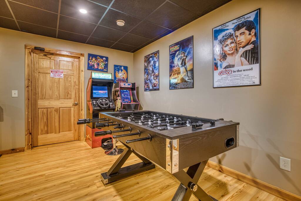 Step into a nostalgic entertainment zone! This view features two old-school arcade games, a foosball table in the foreground, and walls with classic movie posters. A perfect mix of retro fun and cinematic vibes for an unforgettable experience! Step into a nostalgic entertainment zone! This view features two old-school arcade games, a foosball table in the foreground, and walls with classic movie posters. A perfect mix of retro fun and cinematic vibes for an unforgettable experience! - Spacious Cabin, Hot Tub, Theater, Dog Run, FirePit - Ellijay