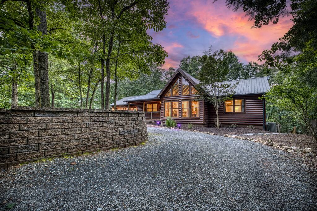 Take in the beauty of this stunning dusk view! The circular drive offers easy access, while the vibrant sunset creates a breathtaking backdrop for the well-lit cabin. A picture-perfect start to your relaxing mountain getaway! Take in the beauty of this stunning dusk view! The circular drive offers easy access, while the vibrant sunset creates a breathtaking backdrop for the well-lit cabin. A picture-perfect start to your relaxing mountain getaway! - Spacious Cabin, Hot Tub, Theater, Dog Run, FirePit - Ellijay