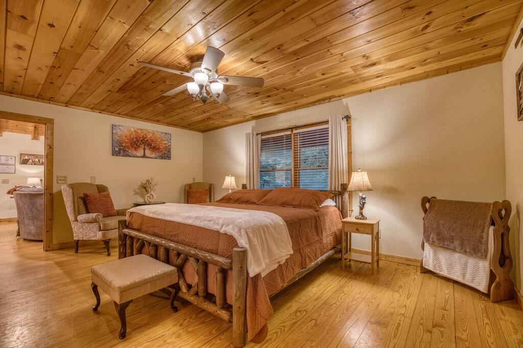 Cozy master bedroom with a king bed, plush bedding, and ceiling fan. Features a sitting area with a chair, spacious walk-in closet, and a private bathroom with modern, soothing fixtures. Cozy master bedroom with a king bed, plush bedding, and ceiling fan. Features a sitting area with a chair, spacious walk-in closet, and a private bathroom with modern, soothing fixtures. - Spacious Cabin, Hot Tub, Theater, Dog Run, FirePit - Ellijay