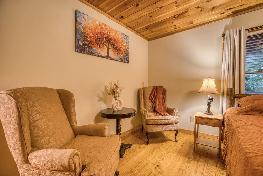 Unwind in the cozy sitting area of the spacious master suite, featuring two comfortable wingback chairs and a stylish coffee table. The perfect spot to relax with a book, a cup of coffee, or simply enjoy a moment of tranquility. Unwind in the cozy sitting area of the spacious master suite, featuring two comfortable wingback chairs and a stylish coffee table. The perfect spot to relax with a book, a cup of coffee, or simply enjoy a moment of tranquility. - Spacious Cabin, Hot Tub, Theater, Dog Run, FirePit - Ellijay