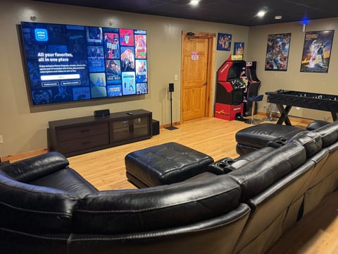 Private theater room with oversized TV, arcade game, foosball, and plush seating