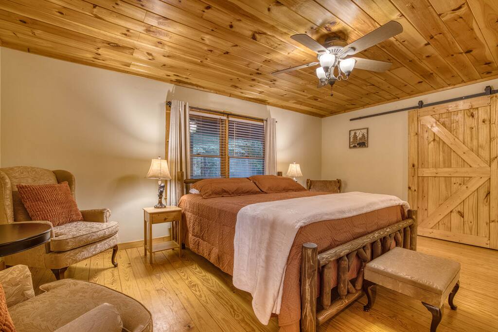 Welcome to the spacious master suite! Enjoy a king bed, barn door closet with a bassinet and playpen for your little one, a full bath, large walk-in closet, and a cozy sitting area to the left. The perfect retreat for relaxation and family comfort! Welcome to the spacious master suite! Enjoy a king bed, barn door closet with a bassinet and playpen for your little one, a full bath, large walk-in closet, and a cozy sitting area to the left. The perfect retreat for relaxation and family comfort! - Spacious Cabin, Hot Tub, Theater, Dog Run, FirePit - Ellijay